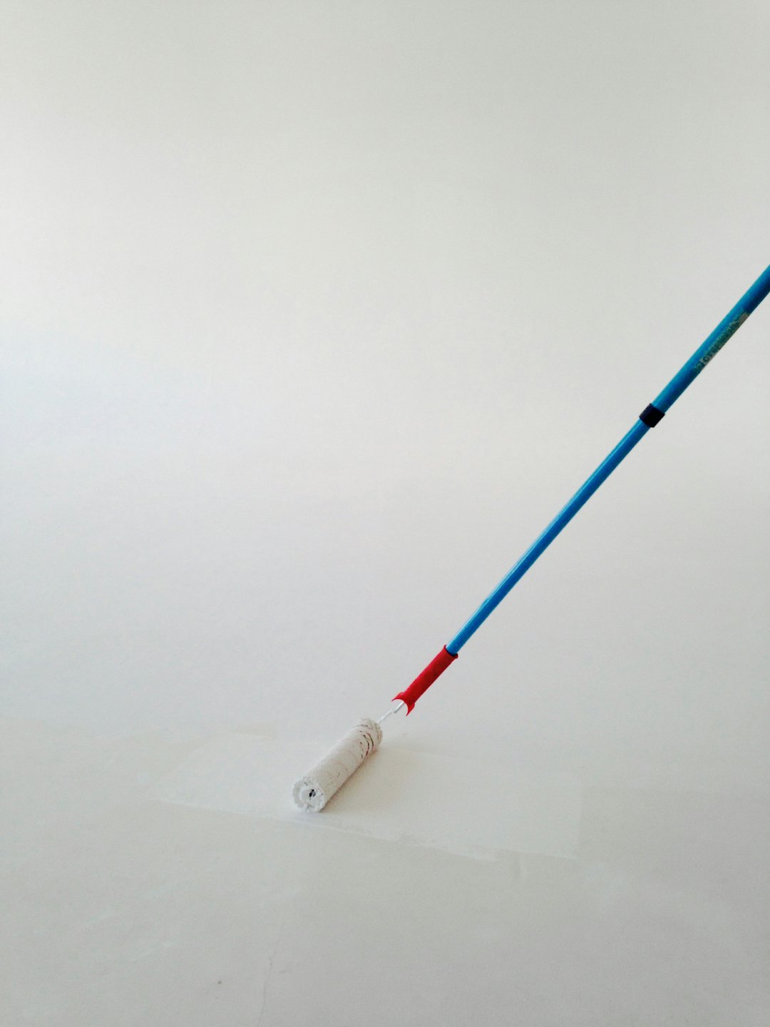 Eine Wand mit einer blauen und roten Farbrolle streichen.